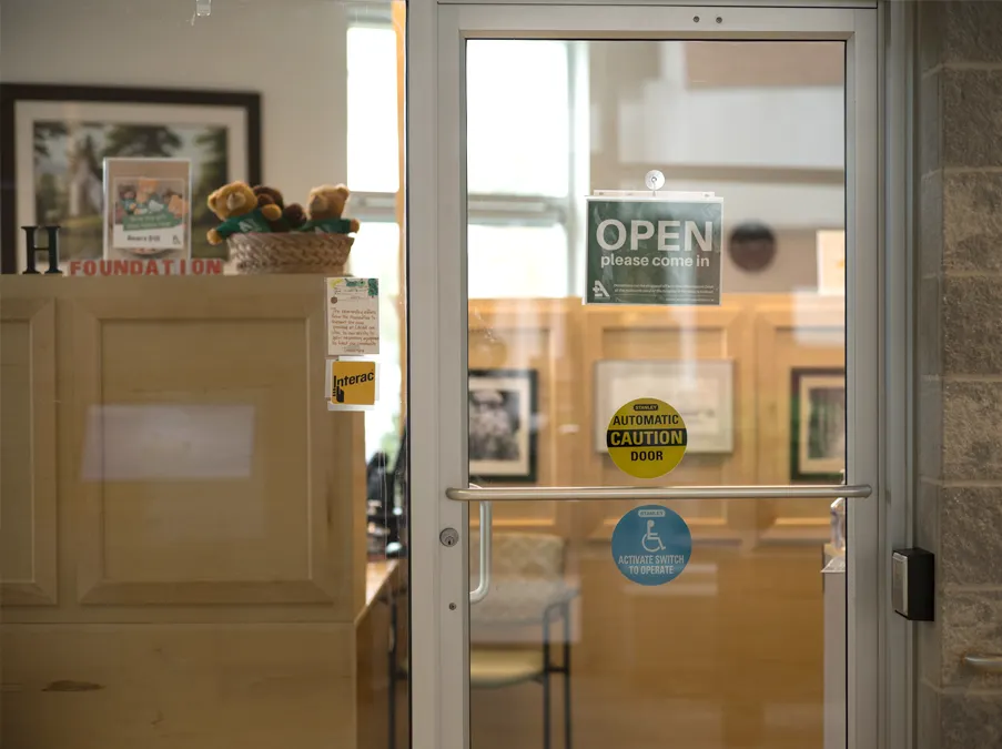 The Hospital Foundation's Office entrance doors with accessibility and automatic door signs.