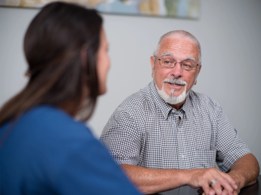 Older patient talks with a community hospital staff member during a visit.